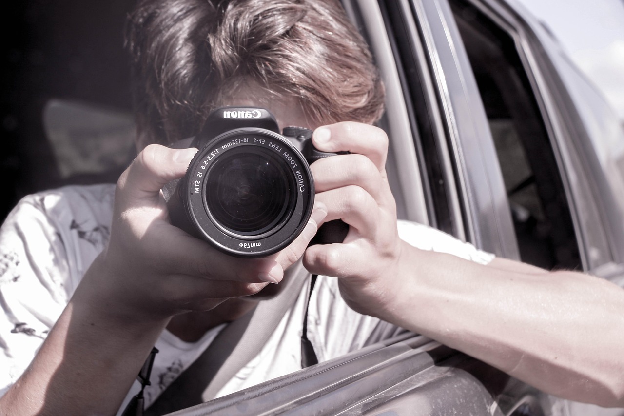 Persoon die door de zoeker van een camera kijkt tijdens een meditatief fotografeermoment buiten
