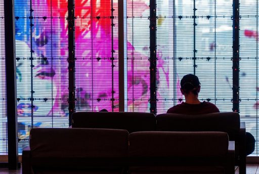Persoon zit alleen bij een raam en kijkt peinzend naar buiten