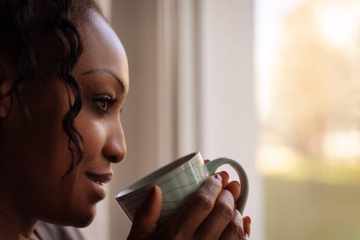Vrouw die rustig koffie drinkt bij een raam op een rustige ochtend