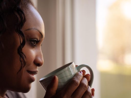 Vrouw die rustig koffie drinkt bij een raam op een rustige ochtend