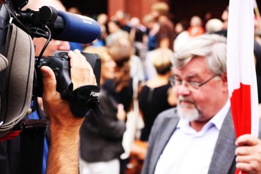 Persoon die thuis op de bank een emotioneel interview bekijkt op televisie