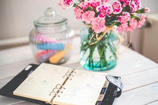 Opengeslagen boeken op een houten bureau met een notitieboekje ernaast