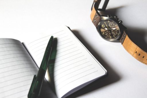 Persoon die een checklist invult in een notitieboekje aan een tafel