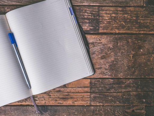 Persoon die persoonlijke doelen opschrijft in een notitieboek aan een bureau