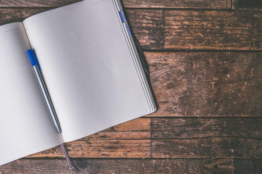 Persoon die persoonlijke doelen opschrijft in een notitieboek aan een bureau
