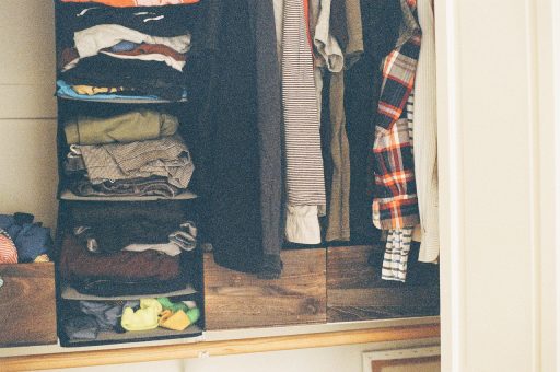 Keurig gevouwen kleding in een houten kast, symbool voor de moeite van loslaten en opruimen