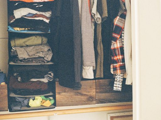 Keurig gevouwen kleding in een houten kast, symbool voor de moeite van loslaten en opruimen
