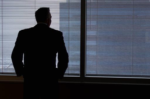 Persoon die nadenkend uit een raam staart, verzonken in gedachten over de toekomst
