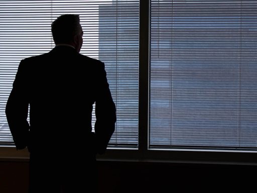 Persoon die nadenkend uit een raam staart, verzonken in gedachten over de toekomst