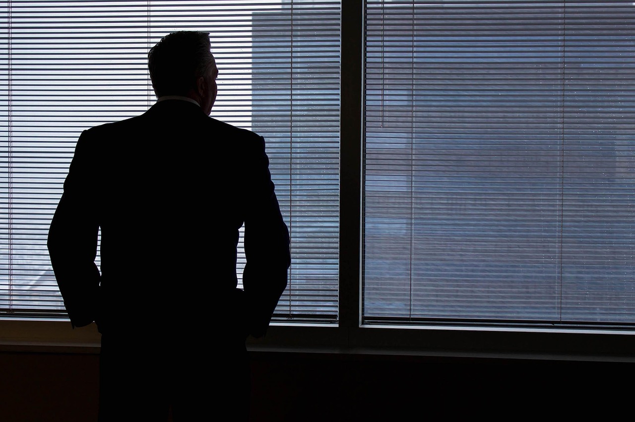 Persoon die nadenkend uit een raam staart, verzonken in gedachten over de toekomst