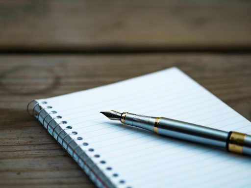 Persoon die uitgaven noteert in een notitieboekje aan een bureau