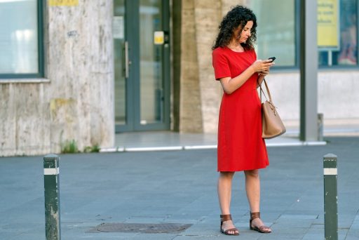 Vrouw kijkt bezorgd naar haar smartphone terwijl ze haar bankrekening bekijkt
