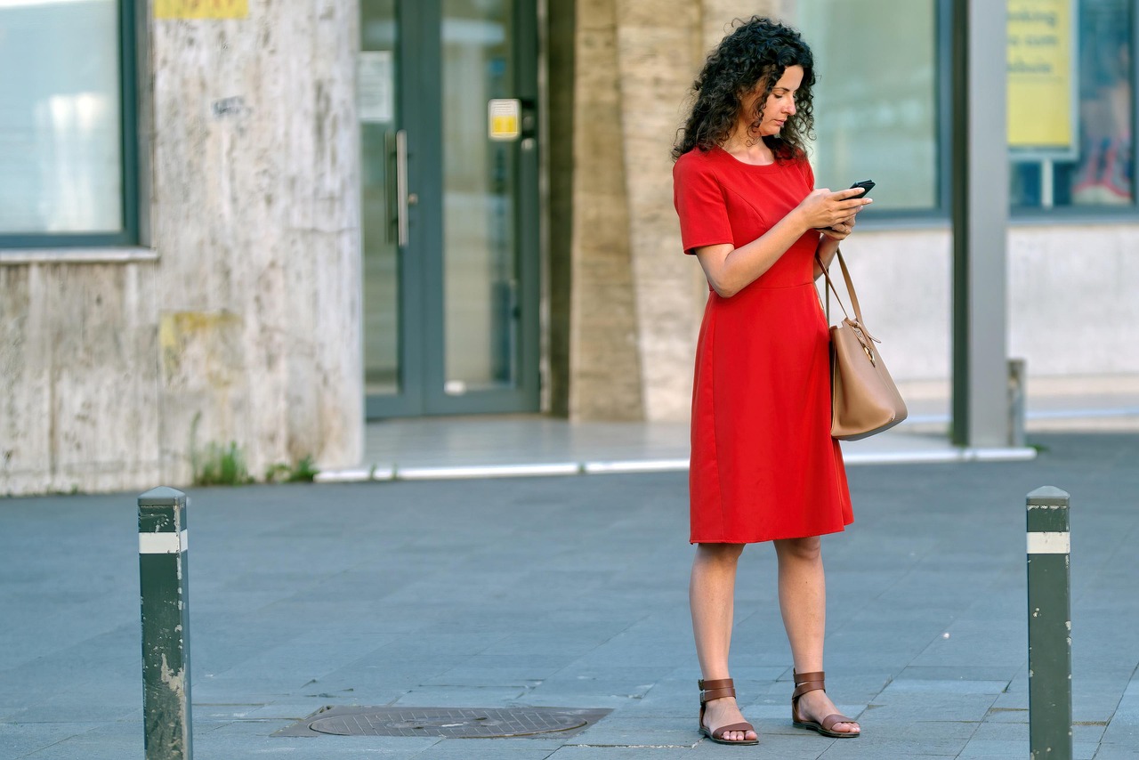 Vrouw kijkt bezorgd naar haar smartphone terwijl ze haar bankrekening bekijkt