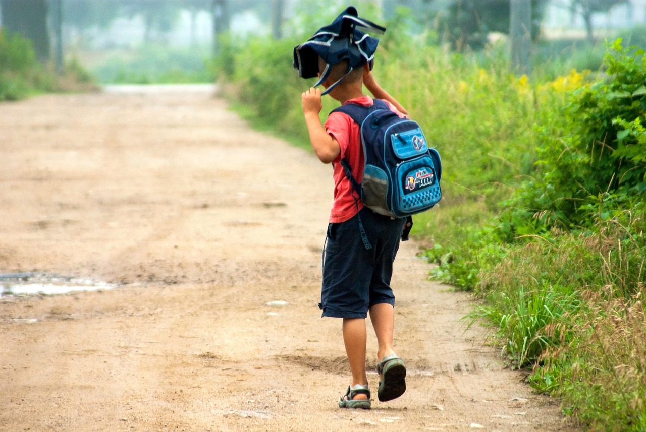 Een moeder staat bij de schoolpoort en zwaait haar kind na op een rustige ochtend